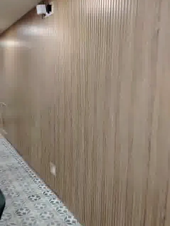 Pasillo con muro en palillería de madera y luz indirecta