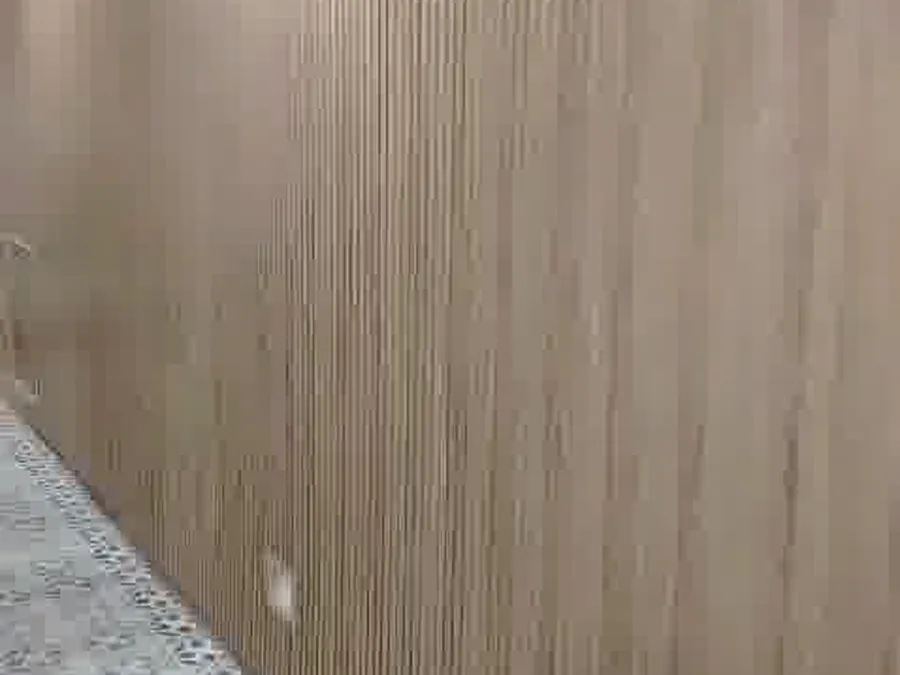 Pasillo revestido en palillería de madera con luz indirecta