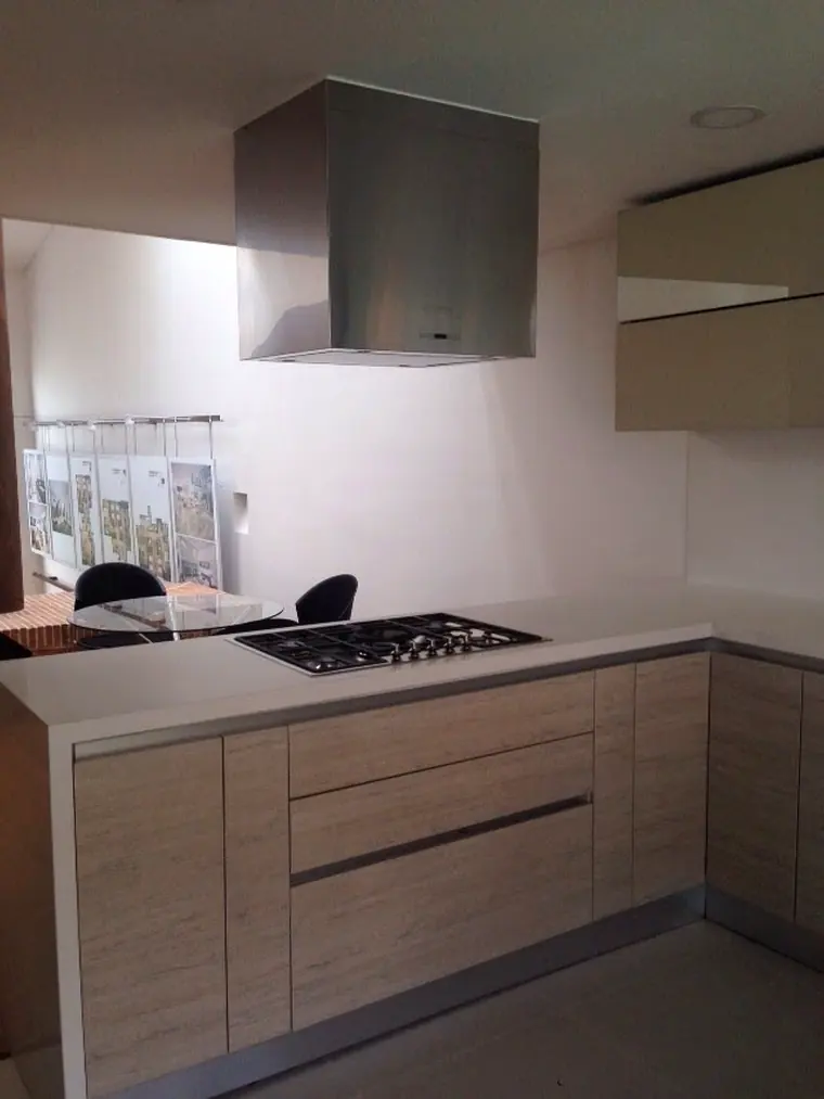 Cocina integral con campana de acero inoxidable y mesón en superficie clara
