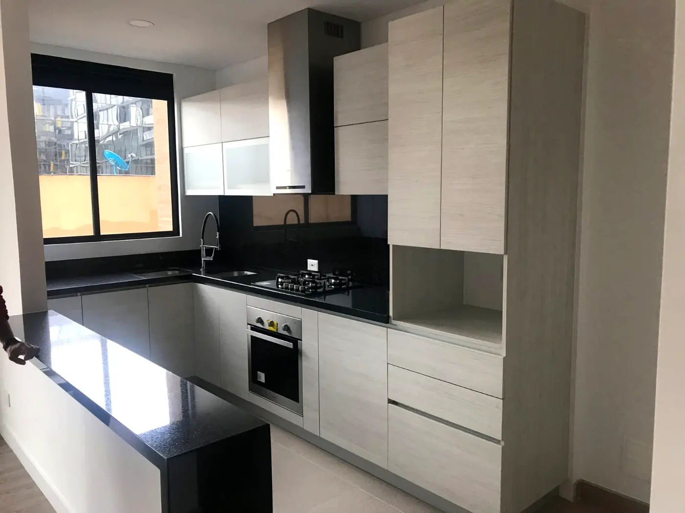 Cocina integral en L con enchape de madera y mesón negro, fabricada en Bogotá